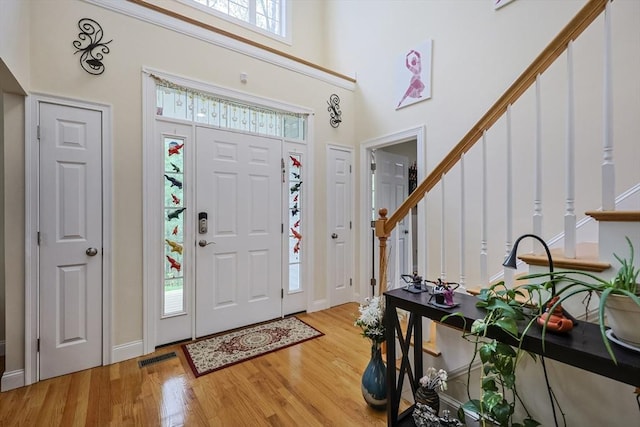 foyer with stairs, a high ceiling, and light wood-style flooring