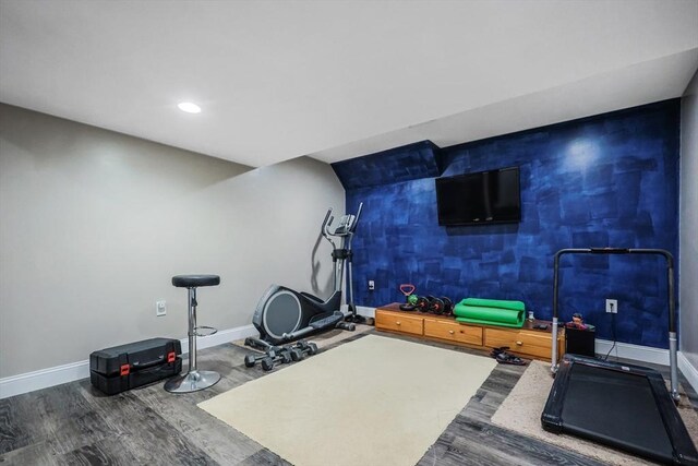 workout room with an accent wall, recessed lighting, baseboards, and wood finished floors