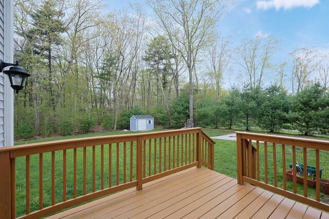 wooden terrace featuring a storage shed, an outbuilding, and a yard