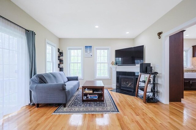 living room featuring a healthy amount of sunlight, a tiled fireplace, and wood finished floors