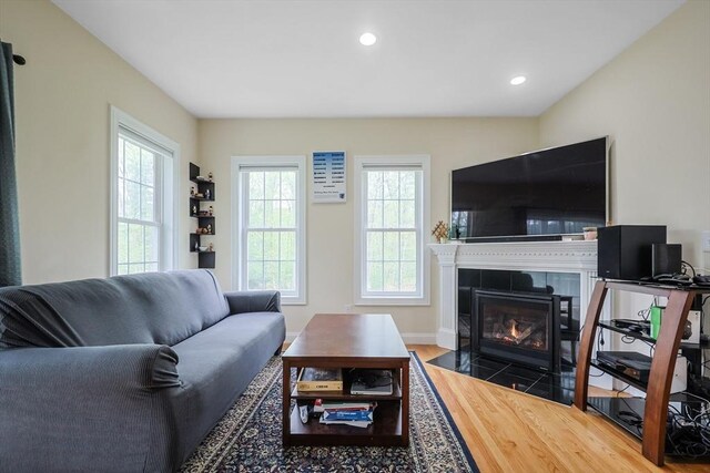 living area with recessed lighting, a tile fireplace, plenty of natural light, and wood finished floors