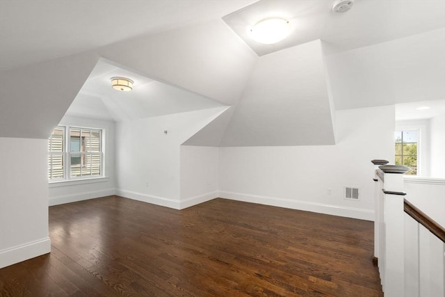 bonus room with visible vents, dark wood finished floors, lofted ceiling, and a healthy amount of sunlight