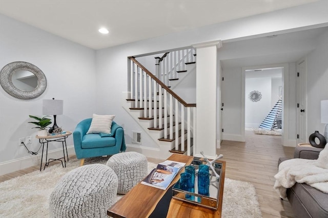 living room featuring baseboards, wood finished floors, visible vents, and stairway