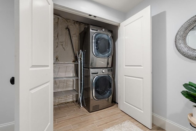 laundry room with stacked washer / drying machine, baseboards, laundry area, and wood tiled floor