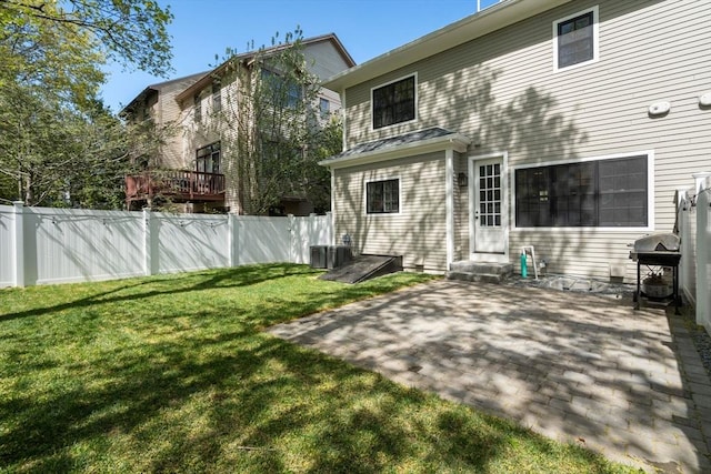 rear view of property featuring fence, entry steps, a lawn, and a patio area