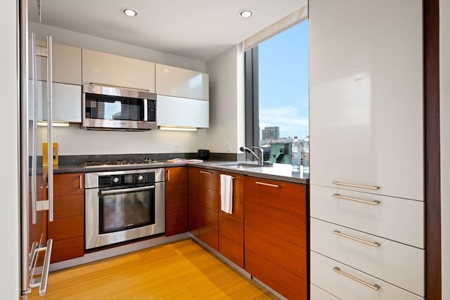 kitchen featuring appliances with stainless steel finishes, sink, and light wood-type flooring