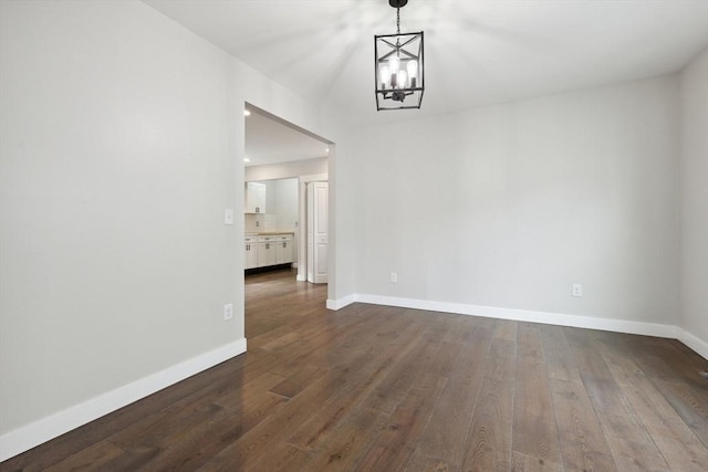 unfurnished dining area featuring baseboards, an inviting chandelier, and dark wood-style flooring