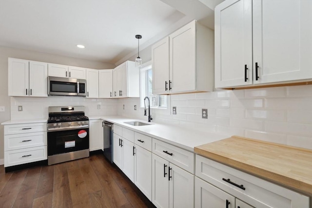 kitchen with backsplash, dark wood-type flooring, appliances with stainless steel finishes, white cabinets, and a sink