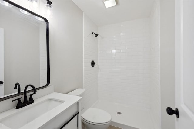 full bath featuring toilet, vanity, and a tile shower