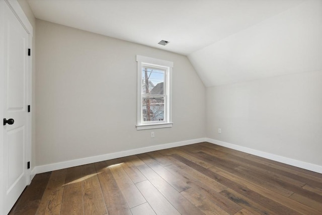 additional living space with baseboards, wood-type flooring, and vaulted ceiling