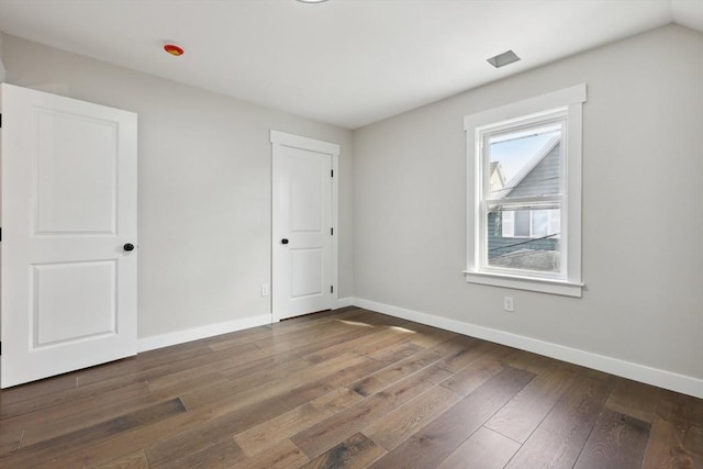 unfurnished room with baseboards and dark wood-style floors