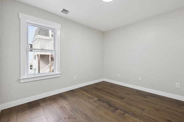 spare room featuring dark wood-type flooring and baseboards