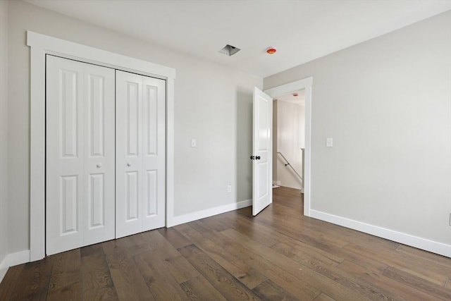 unfurnished bedroom featuring dark wood finished floors, a closet, and baseboards