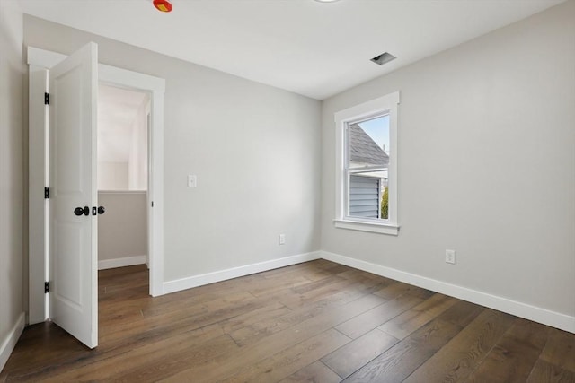 spare room featuring baseboards and dark wood-style flooring