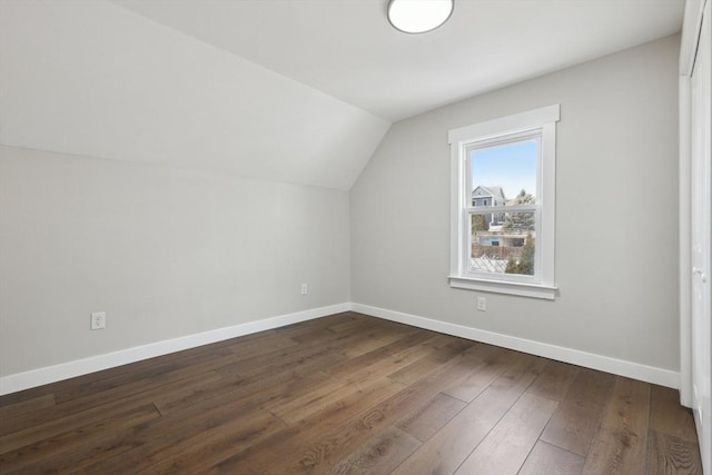 additional living space featuring lofted ceiling, dark wood-style floors, and baseboards