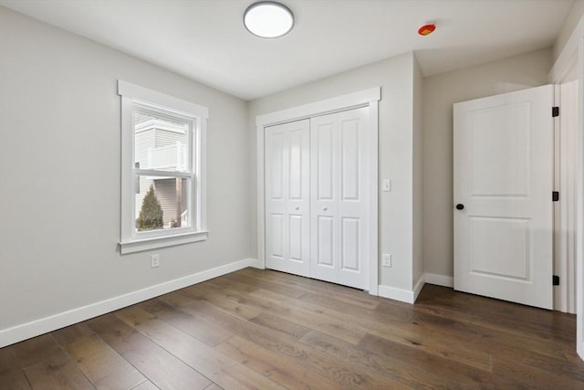 unfurnished bedroom with a closet, baseboards, and hardwood / wood-style floors