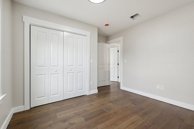 unfurnished bedroom with a closet, baseboards, and wood finished floors