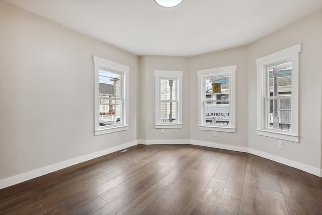 spare room with baseboards and dark wood finished floors