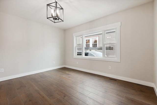 empty room featuring a chandelier, visible vents, baseboards, and dark wood-style flooring