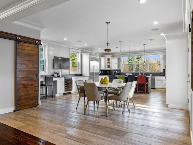 83 Altamont Ave, Melrose, MA 02176 - dining space with beverage cooler, light wood-style flooring, a barn door, ornamental molding, and recessed lighting