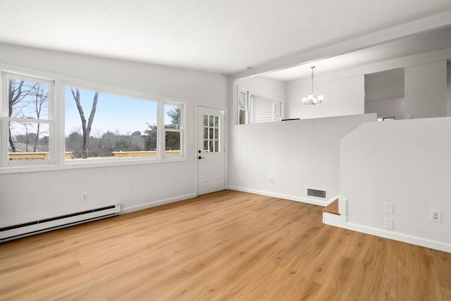 empty room with baseboards, visible vents, light wood finished floors, an inviting chandelier, and baseboard heating