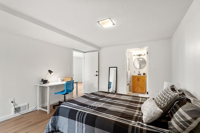 bedroom featuring visible vents, connected bathroom, baseboards, and light wood-style floors