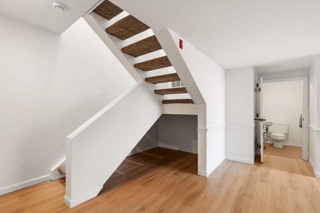 staircase with baseboards and wood finished floors