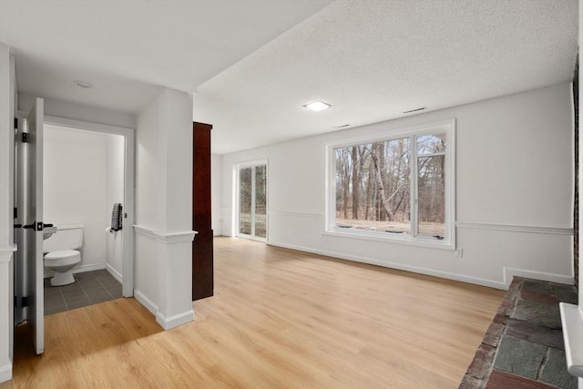 interior space featuring light wood-style flooring, a textured ceiling, and baseboards