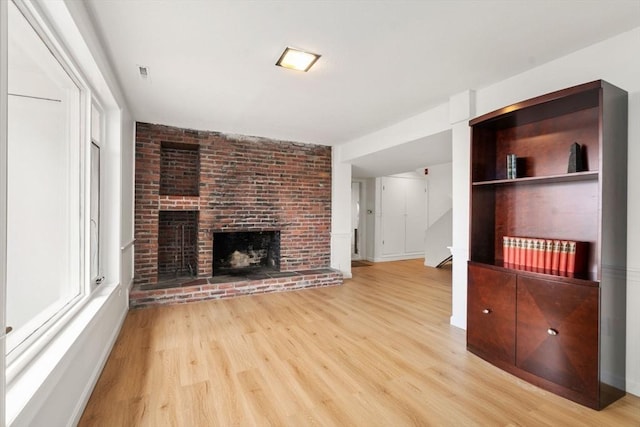 unfurnished living room featuring plenty of natural light, wood finished floors, and a fireplace