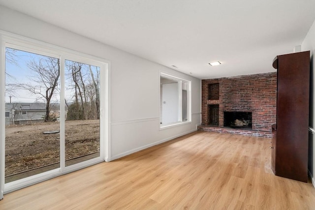 unfurnished living room with a fireplace, light wood-type flooring, and baseboards