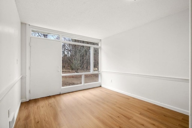 spare room with visible vents, baseboards, a textured ceiling, and wood finished floors