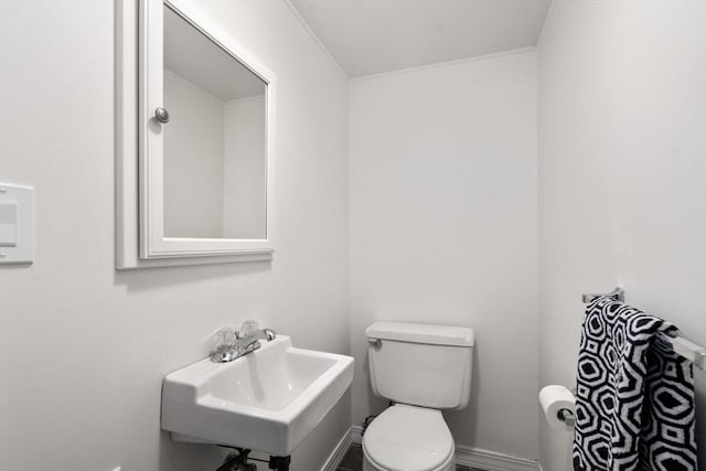 bathroom with toilet, baseboards, and a sink