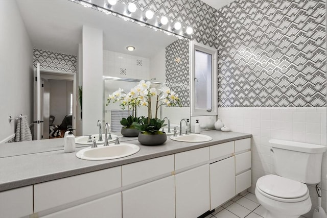 full bath with double vanity, a stall shower, tile patterned floors, and a sink