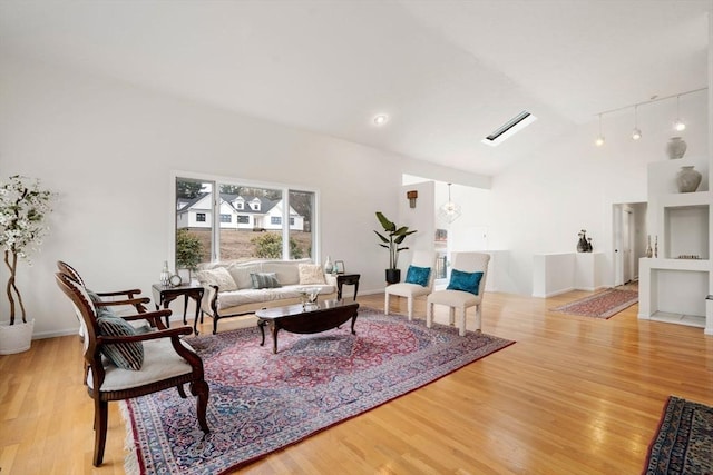 living area featuring baseboards, high vaulted ceiling, and wood finished floors