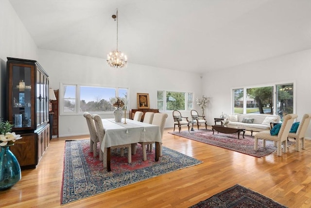 dining area with light wood-style flooring, a notable chandelier, and baseboards