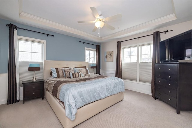 bedroom featuring ornamental molding, a tray ceiling, and light colored carpet