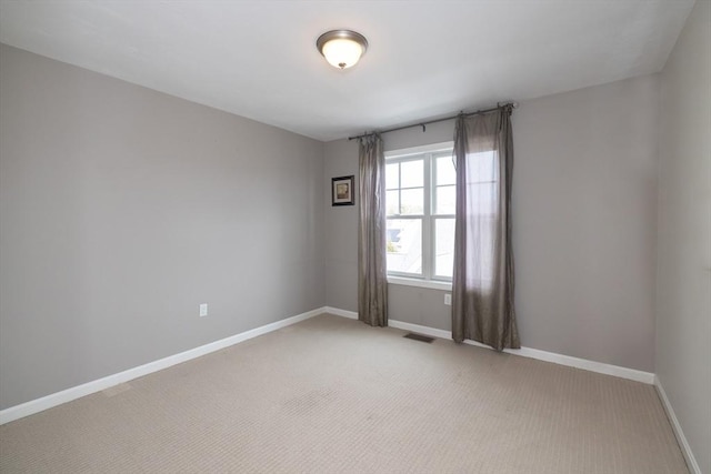 empty room with visible vents, light colored carpet, and baseboards