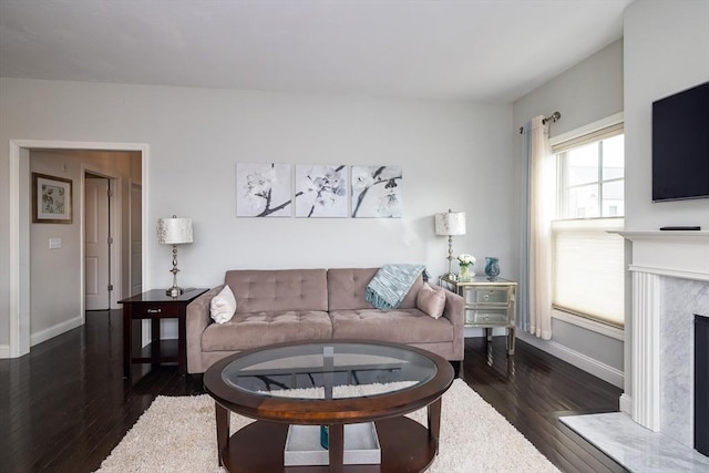 living area with a fireplace, baseboards, and dark wood finished floors