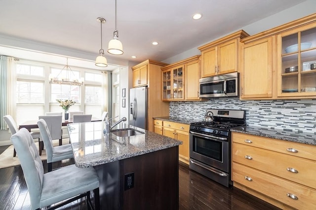 kitchen with glass insert cabinets, appliances with stainless steel finishes, dark stone counters, and a sink