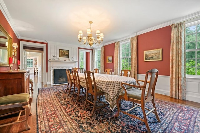 dining space featuring wood-type flooring, ornamental molding, and a chandelier