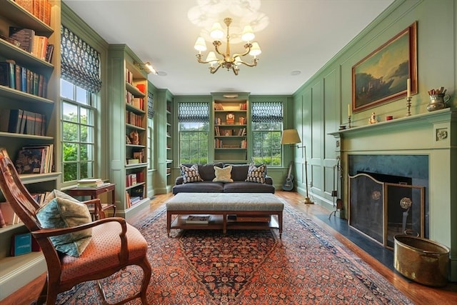 sitting room with a notable chandelier, ornamental molding, and built in features