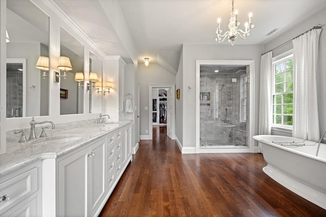 bathroom featuring independent shower and bath, vanity, hardwood / wood-style flooring, and a notable chandelier