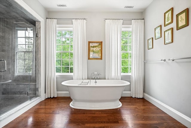 bathroom featuring wood-type flooring, separate shower and tub, and a wealth of natural light