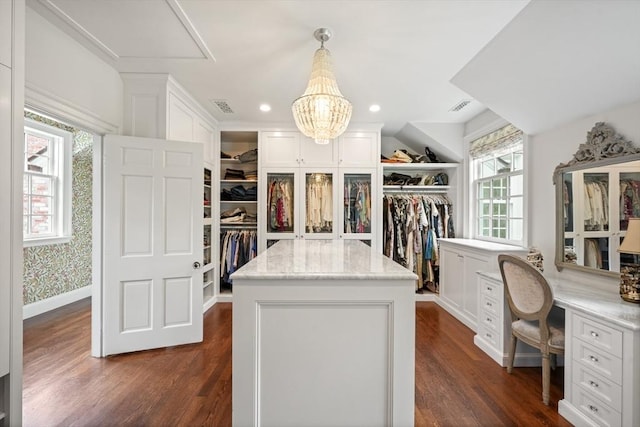 spacious closet with dark hardwood / wood-style flooring and a notable chandelier