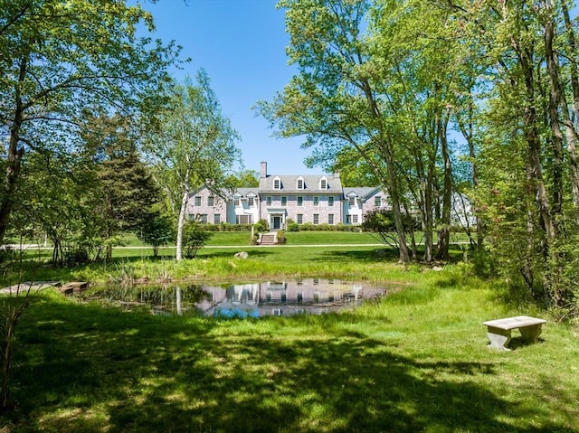 surrounding community with a water view and a lawn