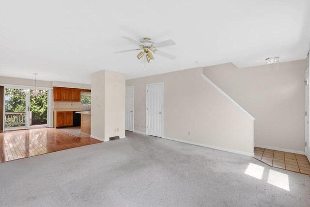 unfurnished living room with baseboards, ceiling fan, visible vents, and light carpet