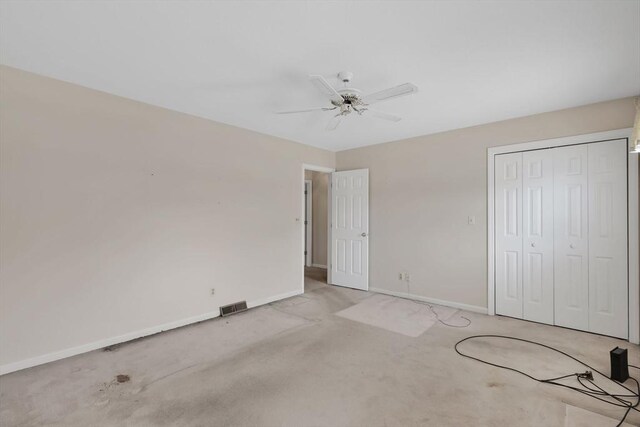 unfurnished bedroom with light carpet, a ceiling fan, baseboards, visible vents, and a closet