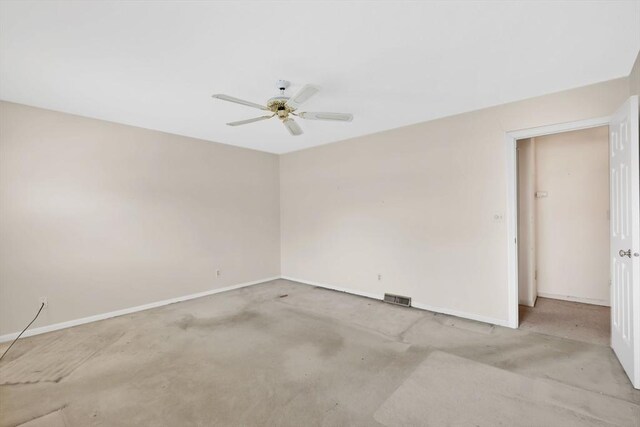carpeted empty room with baseboards, a ceiling fan, and visible vents