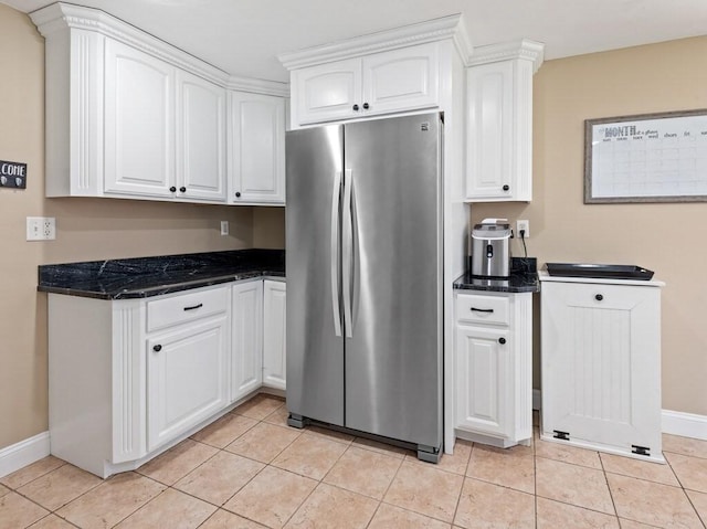 kitchen featuring light tile patterned floors, white cabinetry, freestanding refrigerator, and baseboards