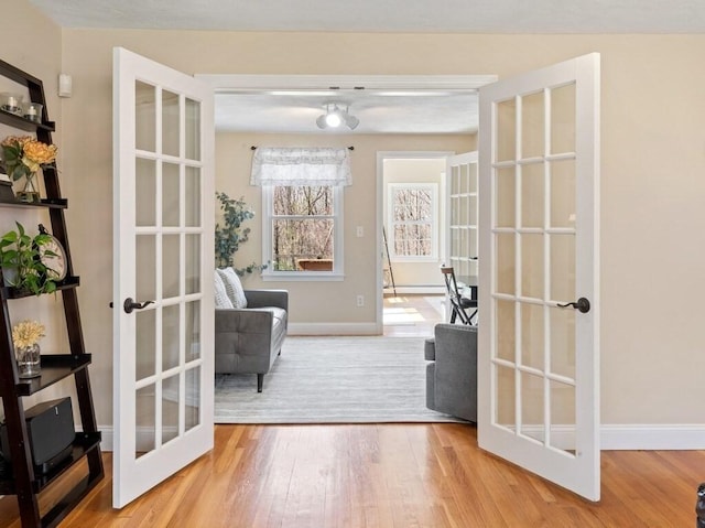 entryway with wood finished floors, french doors, and baseboards